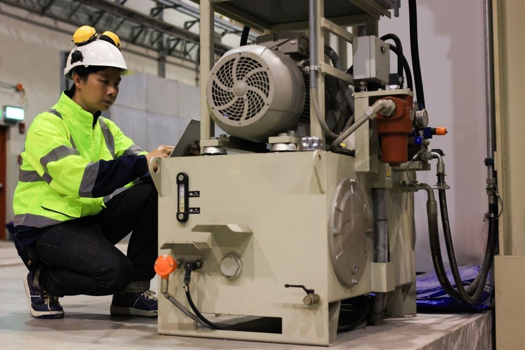 Young Engineer inspecting Hydraulic Power Pack in Factory